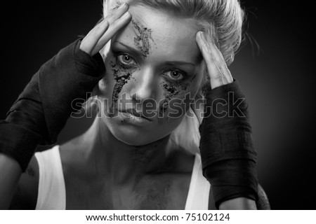 Depressed girl with dirt on her face, closeup. Studio shot.