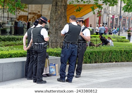 LONDON, UK - JULY 1, 2014: Unknown police officers talking to a stranger on a London street near St. Paul\'s Cathedral.