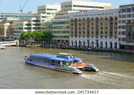 LONDON, UNITED KINGDOM - JULY 1, 2014: A City Cruises tour boat sails on the Thames River near London Bridge Hospital. Thames is the longest river in England with 346 km (215 miles) long.