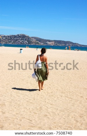 A young woman walking towards the sea in the sun