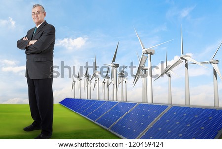 business man push power button,  Panels with solar cells and wind generators on a green field with blue sky