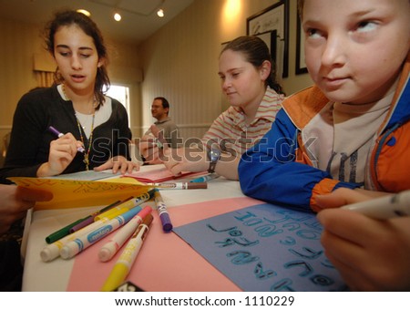 Yechiel Leder (9) (right) ponders what to write on a greeting card alongside Jody Friede (14) (left) and Rivki Lederman (17), all volunteers from Congregation Kehillas Torah who write cards.