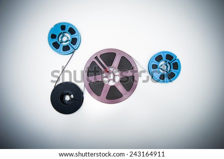 Four big and little size 8mm reels connected with film, vintage color effects