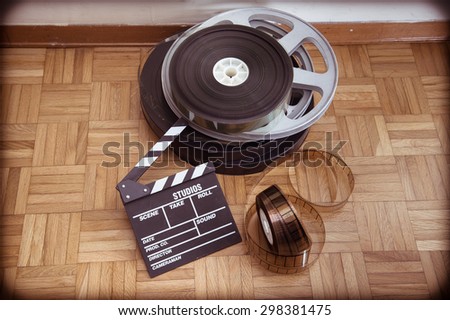Cinema movie clapper board and 35 mm film reel on wooden floor vintage color effect