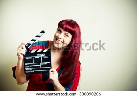 Young woman smiling showing movie clapper board on white background