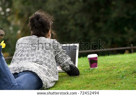 30-35 years old beautiful woman lying grass working on laptop computer in natural in  park