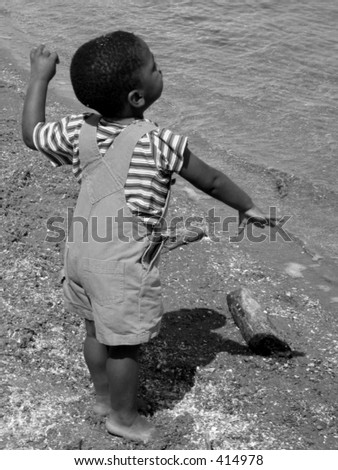 Little boy throwing pebbles into the water.