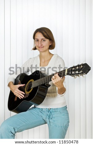 Pretty young woman playing the guitar.