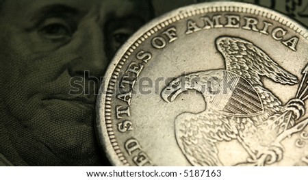 One dollar coin and one hundred dollars bill as a background.
