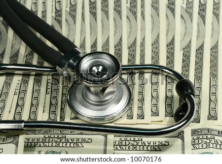 Close-up of stethoscope and one hundred dollars bills