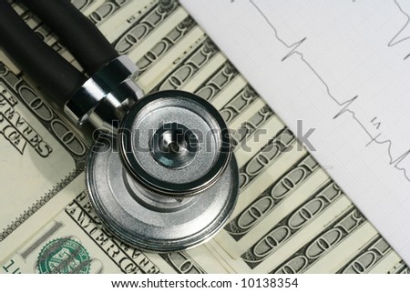 Close-up of stethoscope, EKG printout and one hundred dollars bills