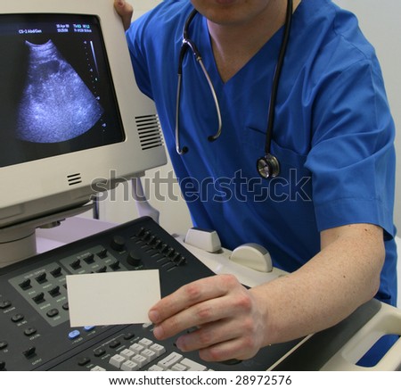 Blank business card in a doctors hand and ultrasound machine as a background