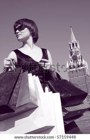 young woman holding shopping bags and tower of Moscow Kremlin as a background