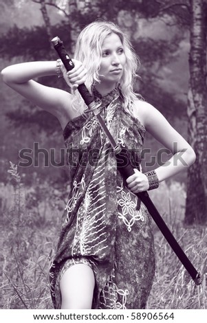 young woman holding katana sword in her hand at summer forest