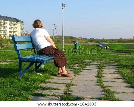 elderly woman look at...  elderly woman is sitting on the bench