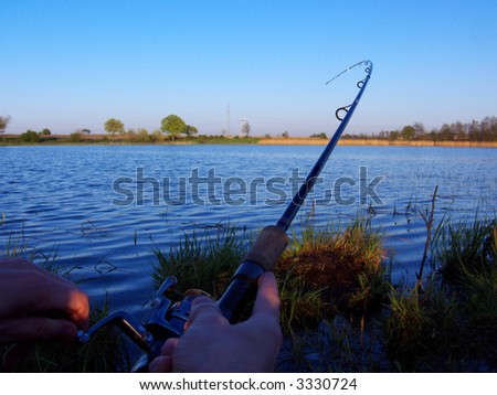 fishing time... sunset, rod and hand angler on the lake, catch of fish