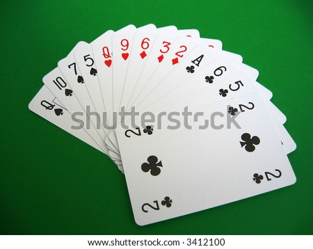 bridge playing - one hand (Q,10,7,5 spades, Q,9 hearts, 6,3,2 diamonds, A,6,5 clubs)  background green, selective focus,
