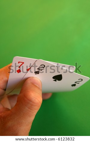 bad cards... 7 diamond and 2 spade in the hand on green background...