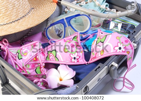 Open suitcase with bikini and sunglasses and beach items