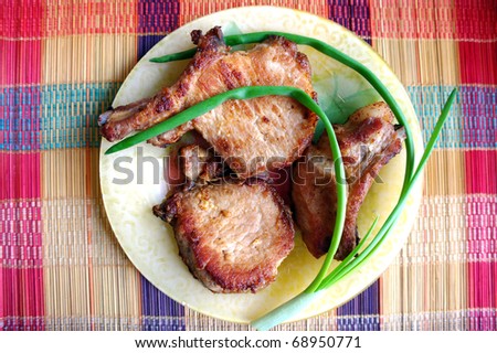 Fried meat with onions on a plate on a striped mat.