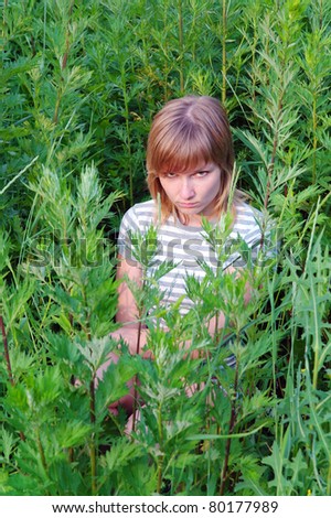 Offended by a sad girl sitting and hiding in the tall grass in the summer, Domodedovo, Moscow Region, Russia