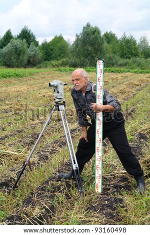 An elderly man with a theodolite to measure the distance field, Tambov region, Russia