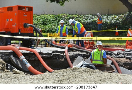 LOS ANGELES, CA - JULY 30, 2014: Workers work in a sink hole to fix a 93 year old broken water main which spilled 20 million gallons of water, flooding parts of West Los Angeles and the UCLA campus.