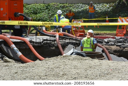LOS ANGELES, CA - JULY 30, 2014: Workers work in a sink hole to fix a 93 year old broken water main which spilled 20 million gallons of water, flooding parts of West Los Angeles and the UCLA campus.