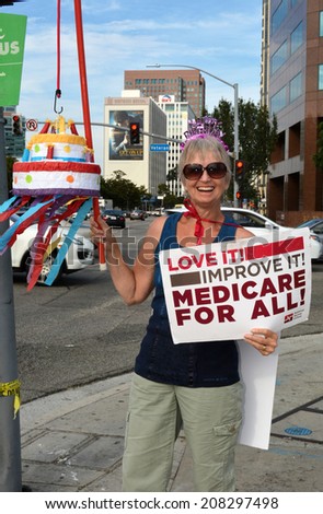 LOS ANGELES, CA - JULY 30, 2014: A demonstrator holding a sign and birthday cake celebrates the 49th birthday of Medicare and advocates Medicare for all during a rally in Los Angeles on July 30, 2014.