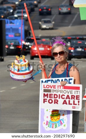 LOS ANGELES, CA - JULY 30, 2014: A demonstrator holding a sign and birthday cake celebrates the 49th birthday of Medicare and advocates Medicare for all during a rally in Los Angeles on July 30, 2014