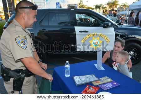 GLENDALE, CA - AUGUST 5, 2014: A mother and child discuss crime prevention with California Highway Patrolman at a National Night Out community fair in Glendale, California on August 5, 2014.