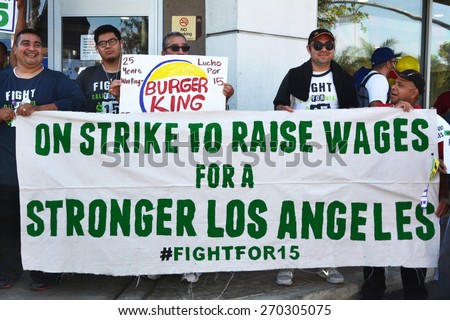LOS ANGELES, CA   APRIL 15, 2015: Protesting fast food workers hold a banner advocating raising the minimum wage for fast food workers during a demonstration in Los Angeles on April 15, 2015.