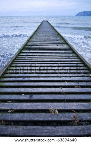 wooden jetty vanishing out into a winter seascape with a way marker at the vanishing point