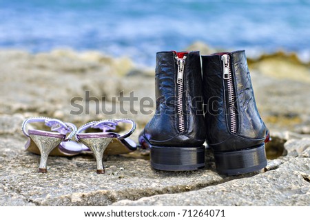 his and hers wedding shoes abandoned on the rocks while the bride and