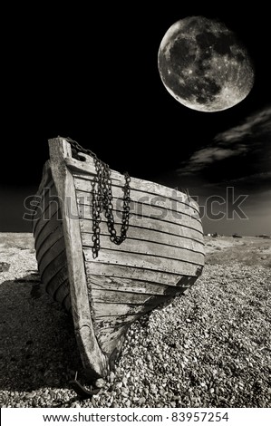  fishing boat on the beach at Dungeness, UK, with a harvest moon in the