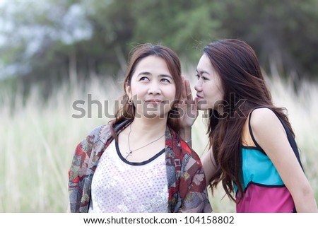 Two young beautiful women talking about something in the park
