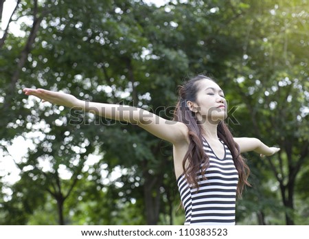 Young woman arms raised enjoying the fresh air in the park