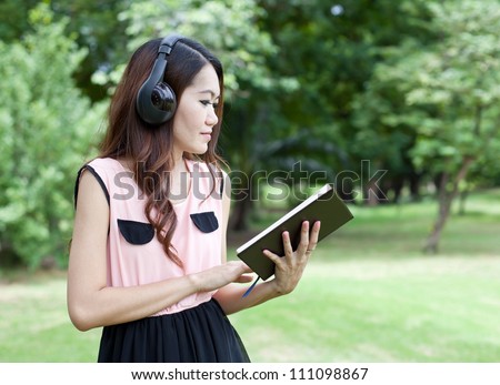 Woman listening to music and reading book