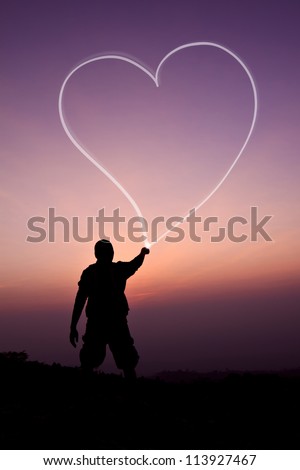 Man drawing heart by flashlight in the air