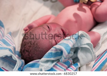 Newborn baby boy resting after being examined in delivery room