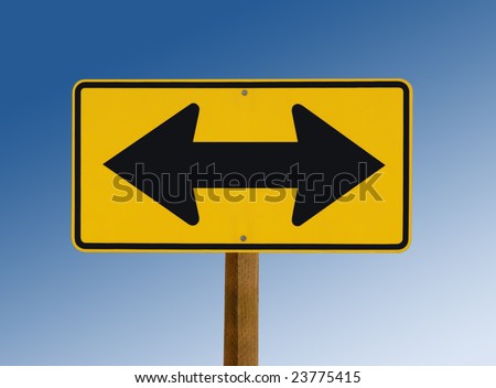 Yellow road sign showing arrows pointing in opposite directions with blue sky behind