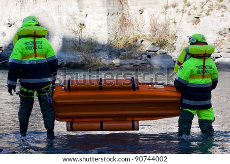 BUSSOLENO, ITALY- DECEMBER 9: Civil defense during rescue mission on December, 9, 2011 in Bussoleno, Italy. Rescue workers try to save a person fallen into the river and move with a stretcher