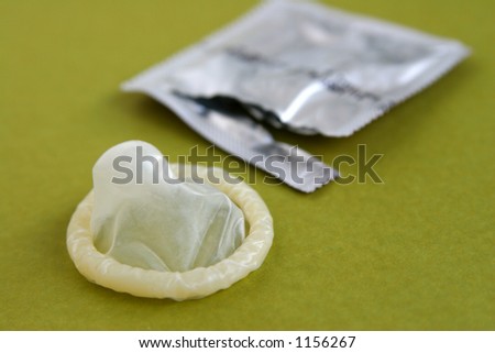 A condom with it's package on a green background