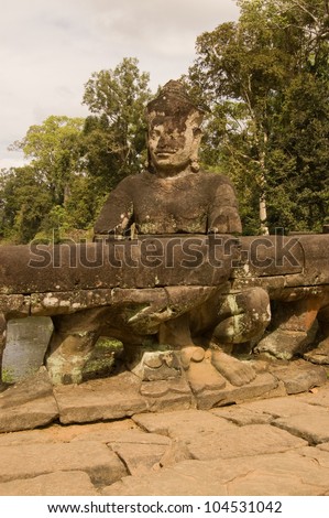 Ancient Khmer statue of an Asura demon pulling on the Naga serpent on the causeway entrance to Preah Khan Temple, Angkor, Cambodia.