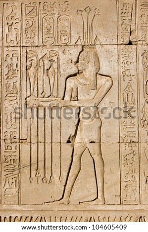 Ancient Egyptian hieroglyphic carving of a priest making an offering to Hapi, the god of the Nile.  Shown by the lotus on his head.  Outer wall of Dendera Temple, near Qena, Egypt.