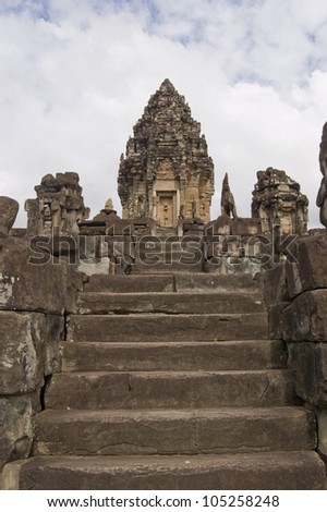 View up stone stairs, lined with imperial lions, towards the central tower of Bakong Temple. Part of Angkor complex, Cambodia.  Ancient Khmer temple, hundreds of years old.