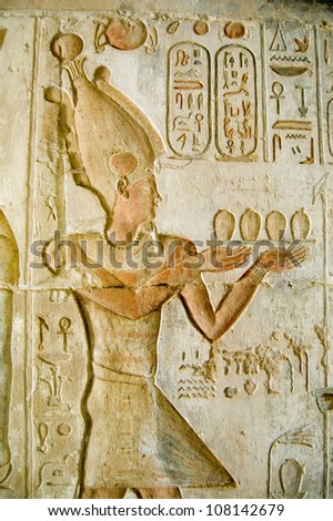 Ancient Egyptian bas relief carving of Pharaoh Ptolemy IV making an offering to the gods.  Temple of Deir el Medina, Luxor, Egypt. Ancient carving over 1000 years old.