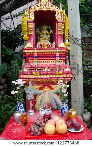 Spirit house in Chiang Mai, Thailand.  Offerings of food, flowers and incense are placed to placate any gods made angry by construction nearby.  In the centre is the Hindu god Vishnu.