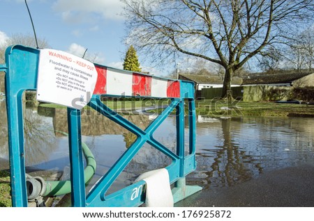 BASINGSTOKE, HAMPSHIRE - FEBRUARY 16 2014: Barrier and warning sign by flood waters in Buckskin, Basingstoke.  Water levels have risen and flooded dozens of homes after many days of heavy rain.