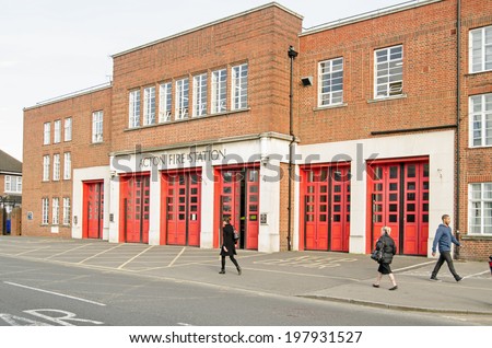 LONDON, ENGLAND - MARCH 15, 2014: Pedestrians walk past Acton Fire Station in West London, part of the London Fire Brigade network.